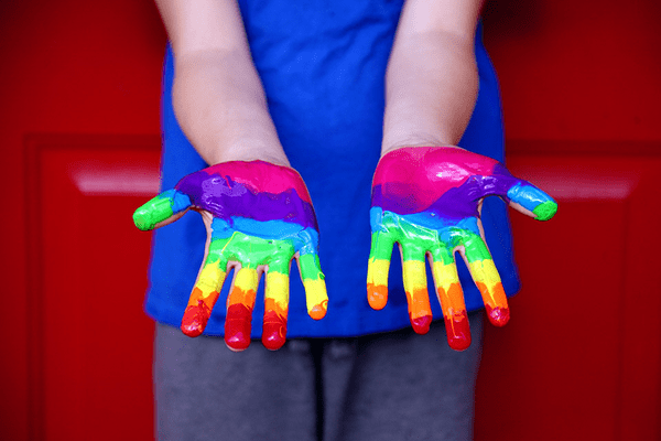 child with rainbow paint on hands